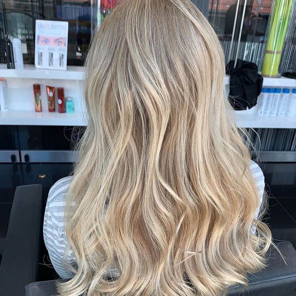 Eine Frau mit langen blonden Haaren sitzt in einem Stuhl in einem Salon.