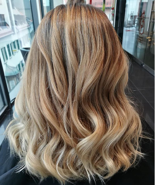 Eine Frau mit blonden Haaren sitzt vor einem Fenster.