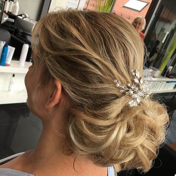 Eine Frau trägt ihr Haar zu einem Dutt hochgesteckt und einen Kopfschmuck aus Perlen.