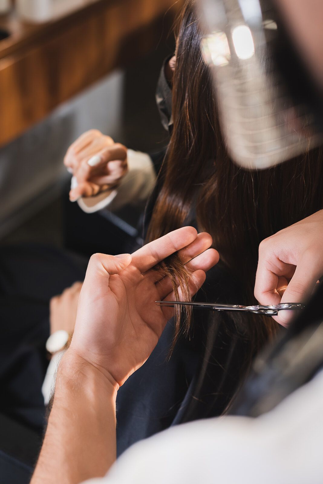 Eine Frau lässt sich in einem Salon von einem Friseur die Haare schneiden.