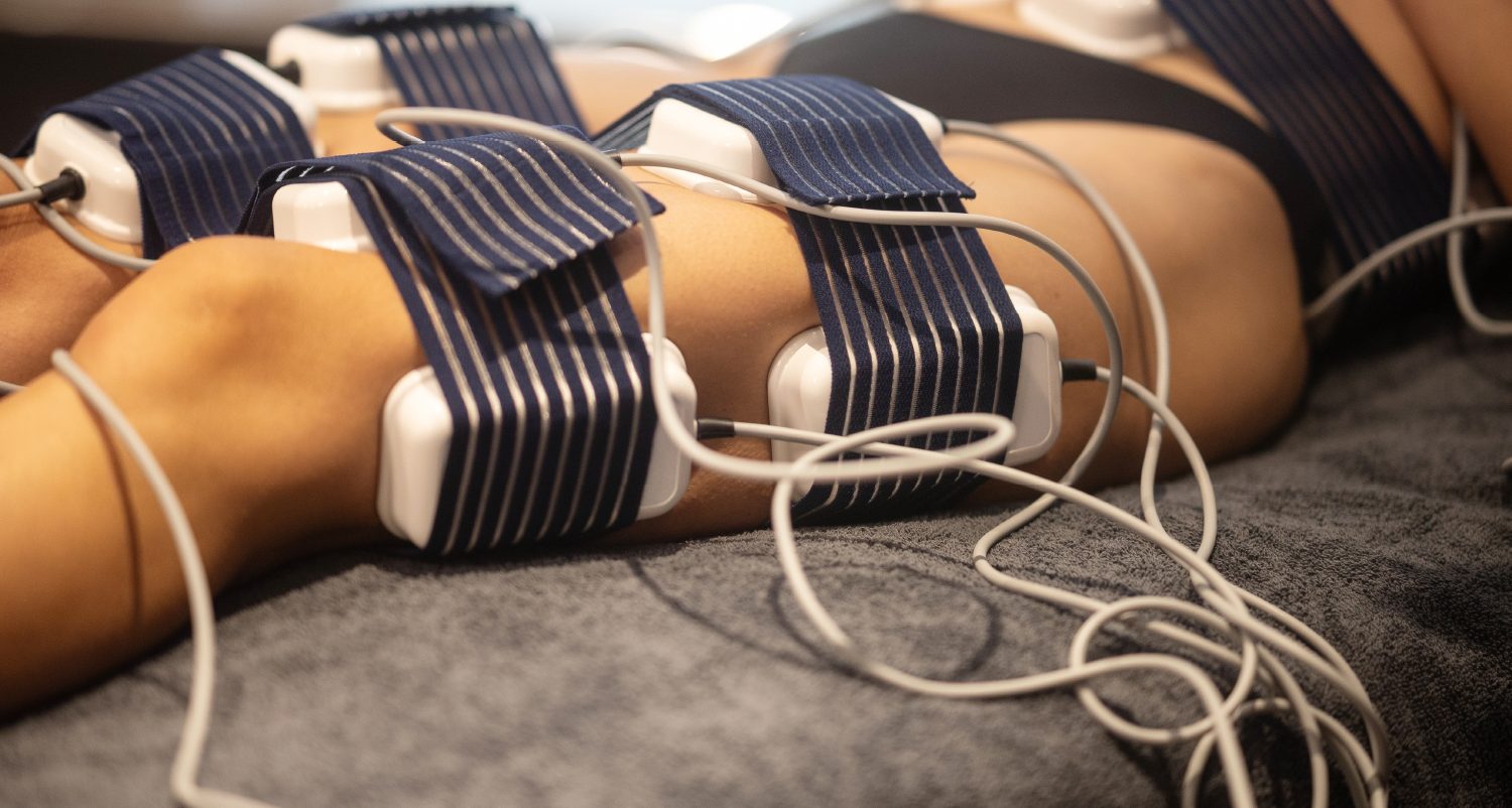 Eine Frau liegt mit vielen Kabeln am Körper auf einem Bett.