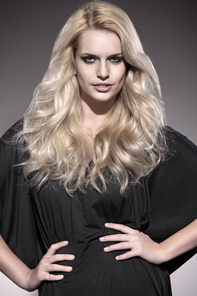 Eine Frau mit langen blonden Haaren trägt ein schwarzes Kleid.