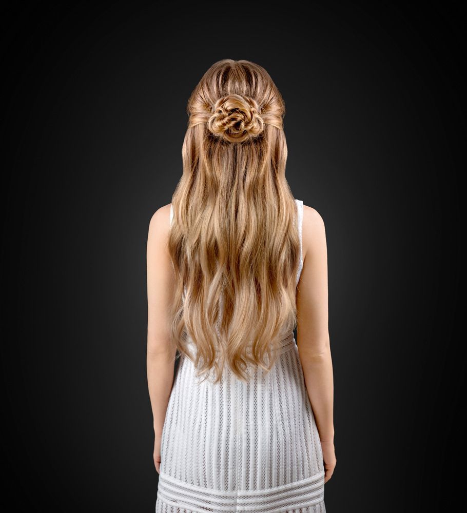 Die Frau trägt ein weißes Kleid und hat ihre Haare zu einem Dutt hochgesteckt.