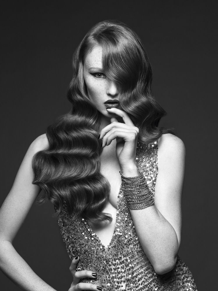 Ein Schwarzweißfoto einer Frau in einem Kleid mit langen, welligen Haaren.