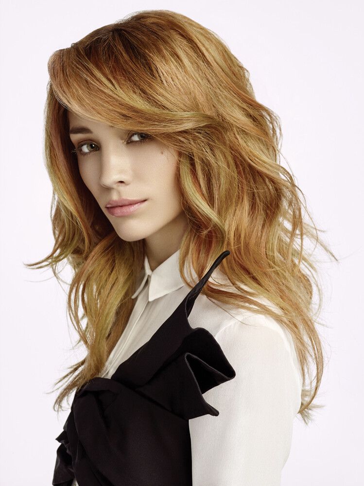 Eine Frau mit langen roten Haaren trägt ein weißes Hemd und ein schwarzes Kleid.