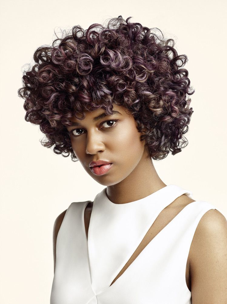 Eine Frau mit lockigem Haar trägt ein weißes Kleid