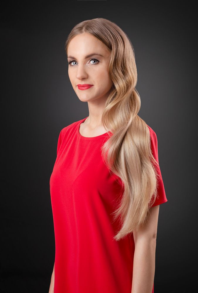 Eine Frau in einem roten Kleid steht vor einem schwarzen Hintergrund.