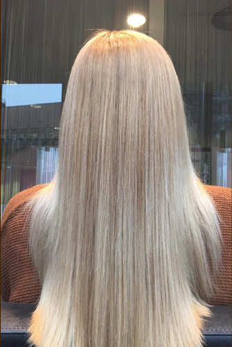 Eine Frau mit langen blonden Haaren sitzt vor einem Spiegel.