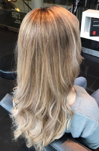 Eine Frau mit langen blonden Haaren sitzt in einem Stuhl in einem Salon.