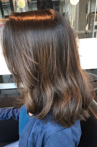 Eine Frau mit langen braunen Haaren sitzt auf einem Stuhl.