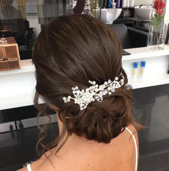 Eine Frau trägt ihr Haar zu einem Dutt mit einem Blumenkamm.