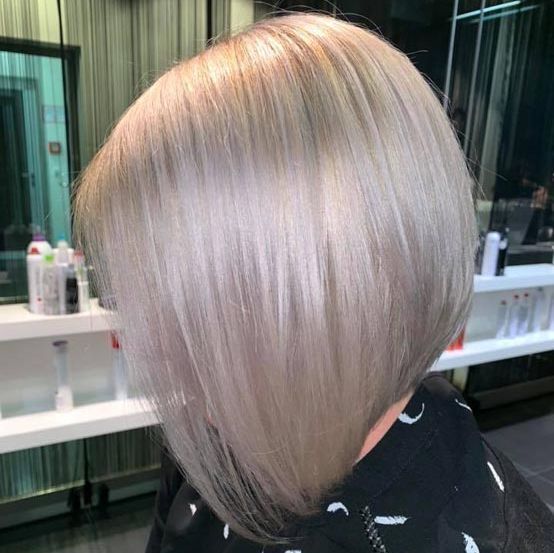 Eine Frau mit blondem Haar lässt sich in einem Salon die Haare schneiden.