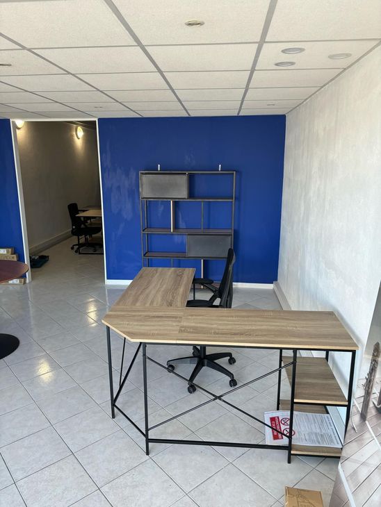 Petit bureau avec un mur d'accent bleu, un bureau, des étagères, une chaise et un sol carrelé ; porte à gauche.