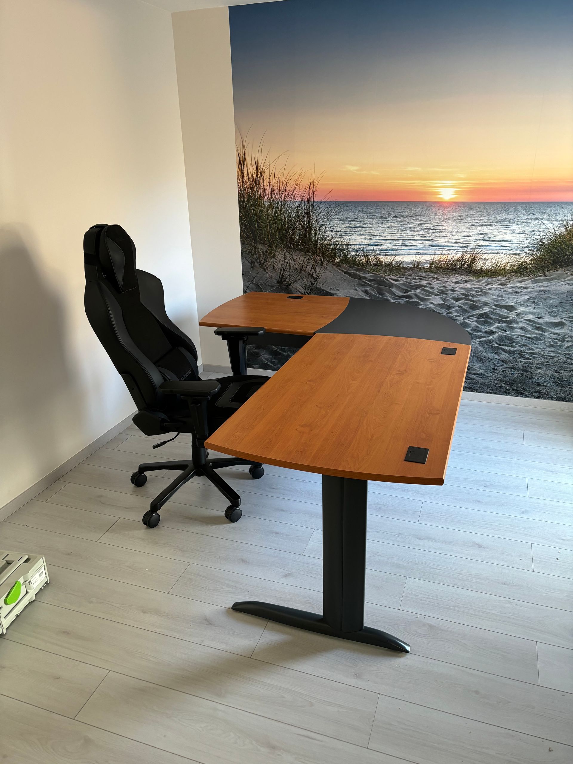 Bureau et chaise face à une fresque murale représentant un coucher de soleil sur la plage et l'océan.