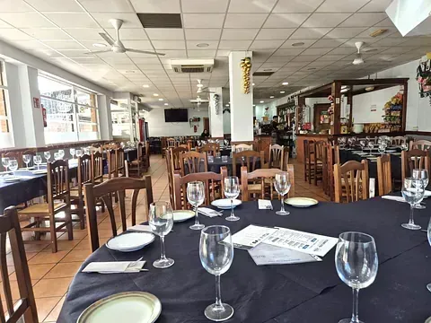 Un restaurante lleno de mesas y sillas con platos y copas de vino sobre ellas.