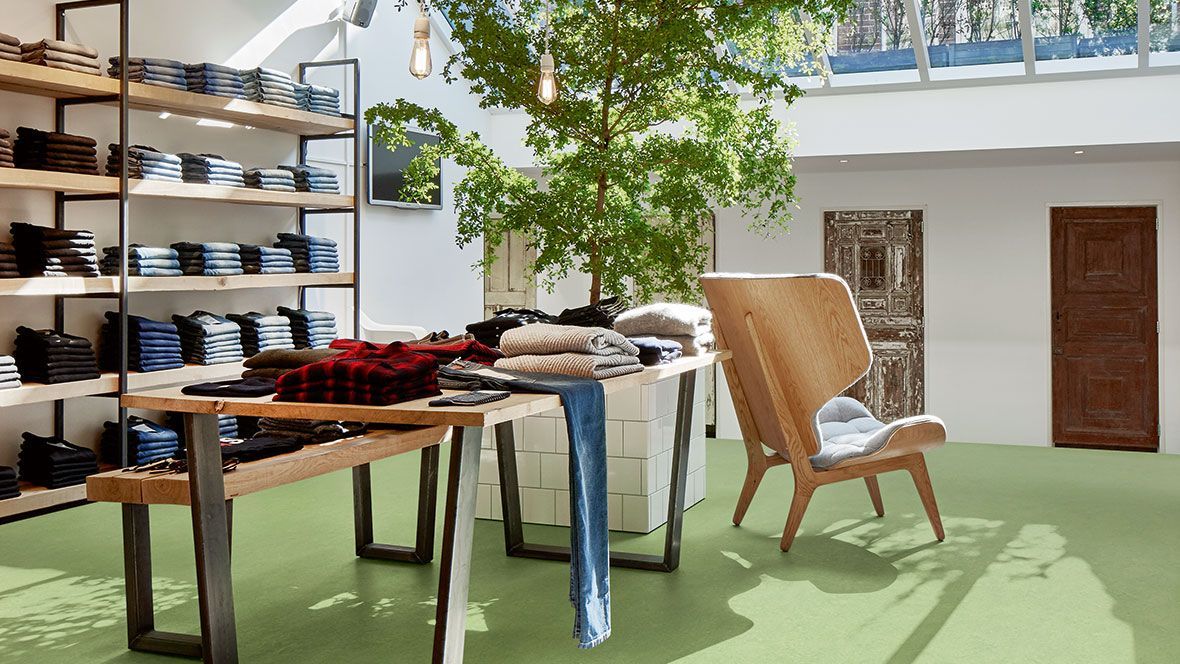 Ein Laden mit Tischen und Stühlen und einem Baum in der Mitte des Raumes.