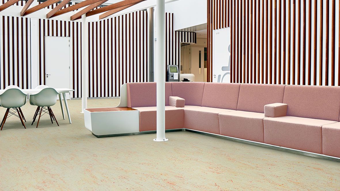 Ein Wohnzimmer mit einer rosa Couch und gestreiften Wänden.