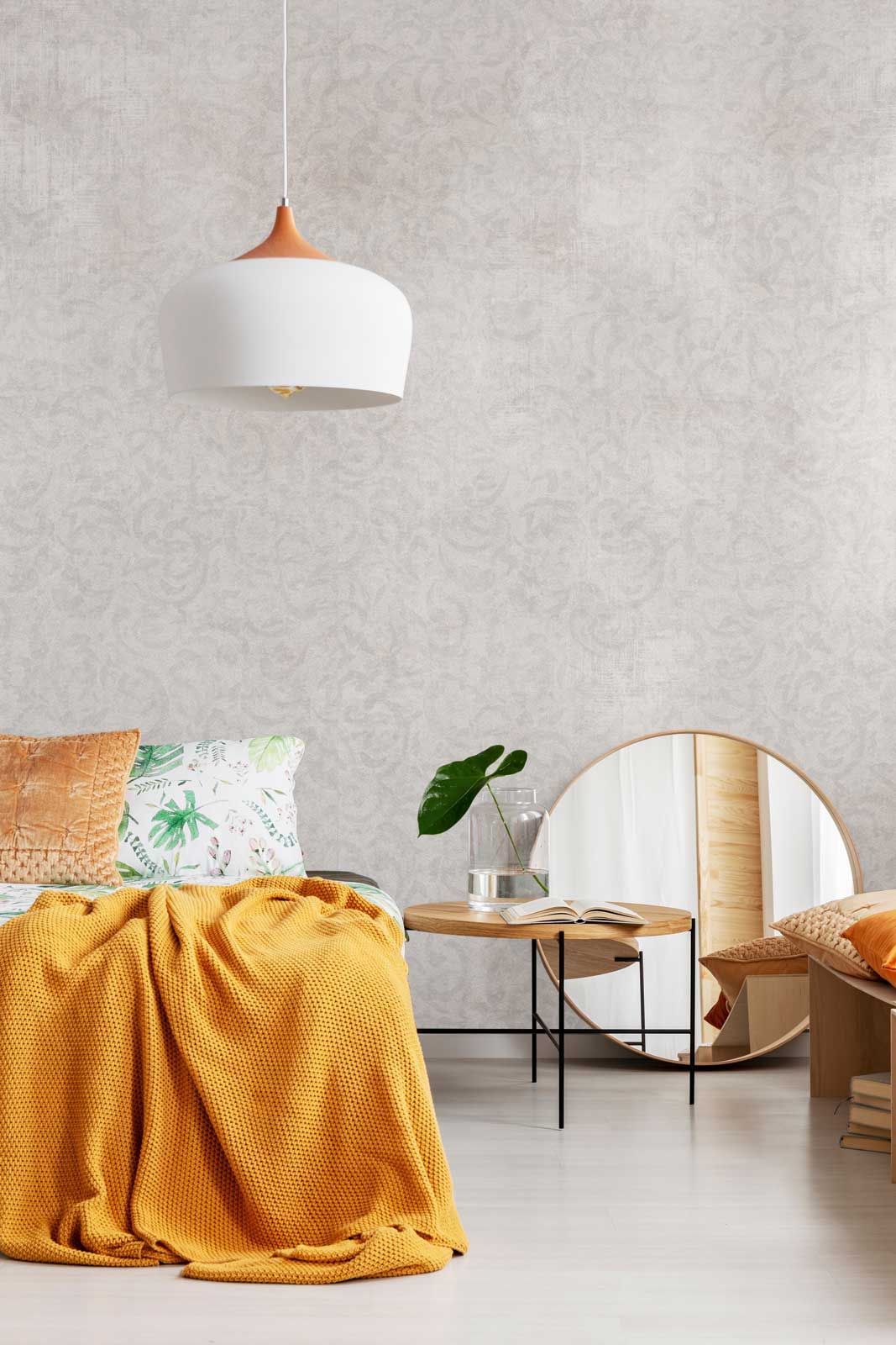 Ein Schlafzimmer mit Bett, Tisch, Spiegel und Lampe.