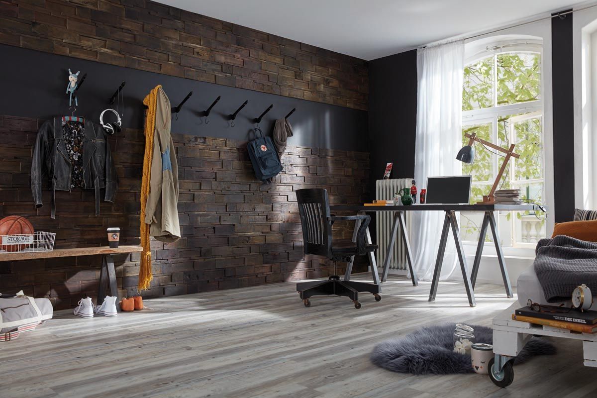 Ein Raum mit einer Ziegelwand und einem Schreibtisch mit einem Laptop darauf