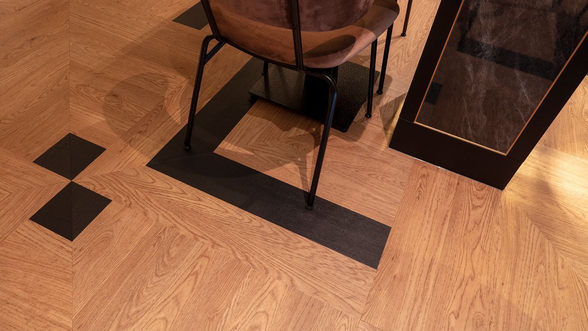 Ein Holzboden mit einem Stuhl und einem Tisch in einem Zimmer.