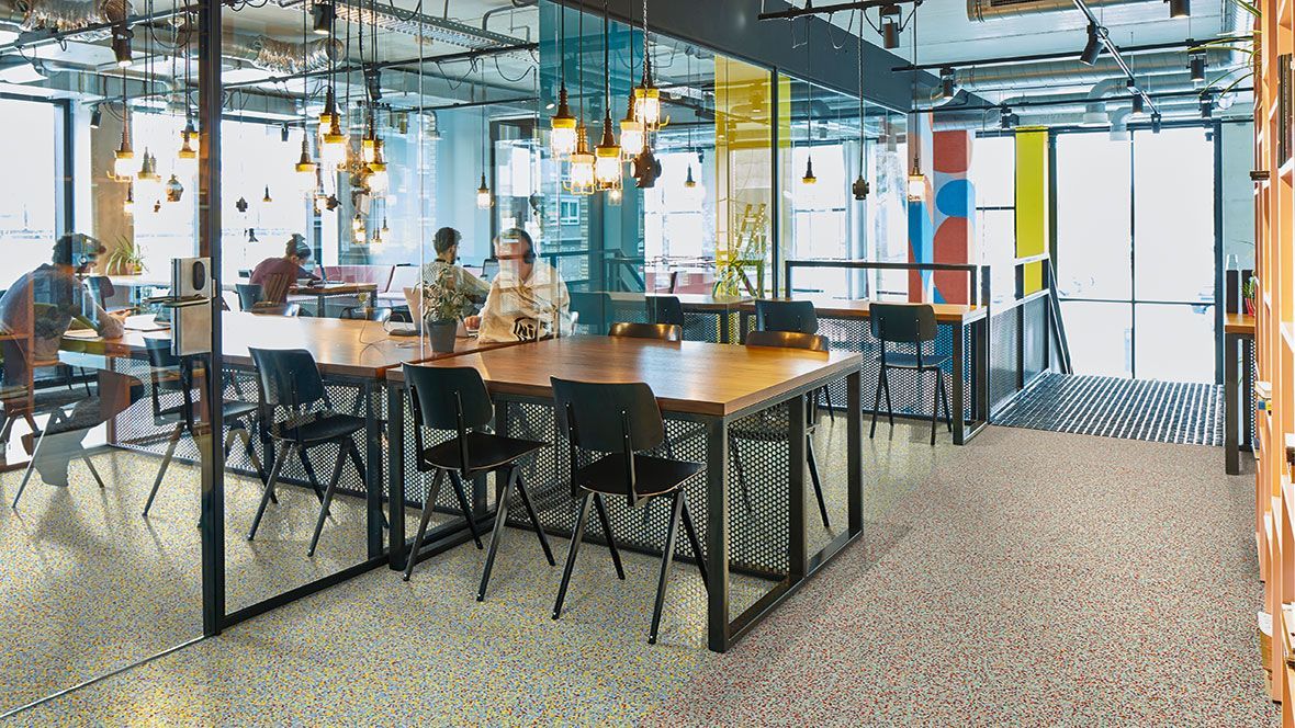 Eine Gruppe von Menschen sitzt in einem großen Raum an Tischen.