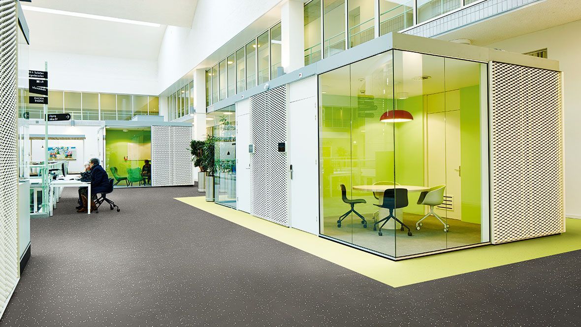 Ein Mann sitzt an einem Schreibtisch in einem Konferenzraum in einem Bürogebäude.