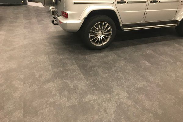 Ein weißer Geländewagen ist auf einem Betonboden in einer Garage geparkt.