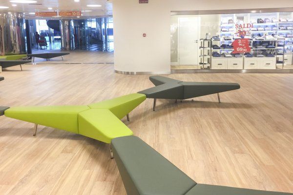 Eine Reihe grüner und grauer Bänke vor einem Geschäft