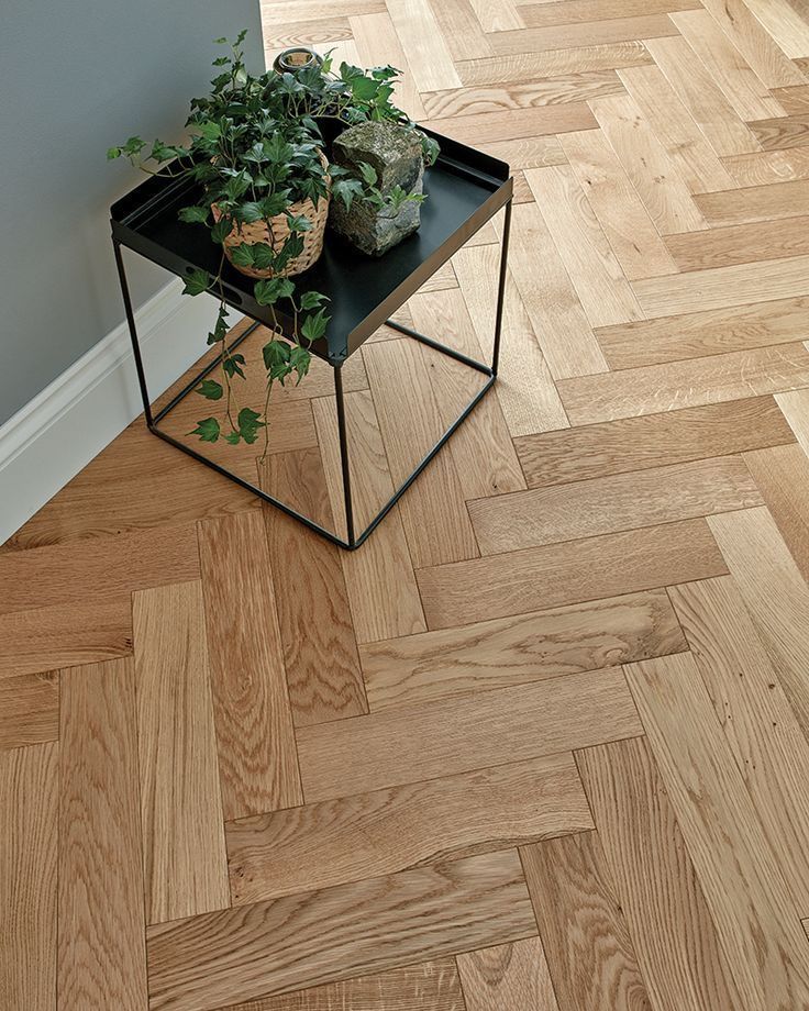 Ein kleiner Tisch mit einer Pflanze darauf auf einem Holzboden.
