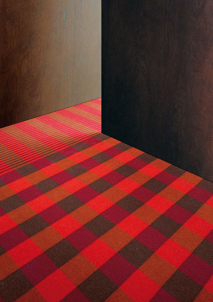 Eine Zimmerecke mit einem rot-braun karierten Teppich