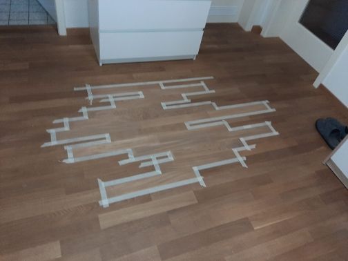 Ein Labyrinth aus Klebeband auf einem Holzboden