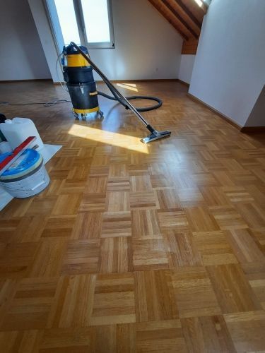 Ein Staubsauger steht auf einem Holzboden in einem Zimmer.