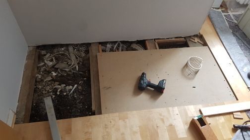 Auf einem Holzboden steht eine Bohrmaschine.