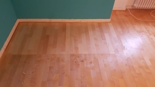 Ein Holzboden in einem Raum mit einer blauen Wand.