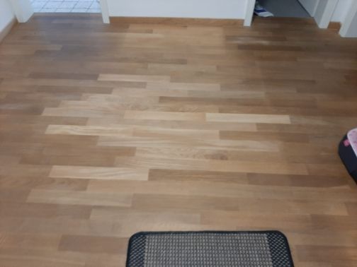 Ein Holzboden mit einer schwarzen Matte darauf in einem Raum.