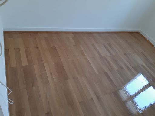 Ein Raum mit Holzboden und weißen Wänden.