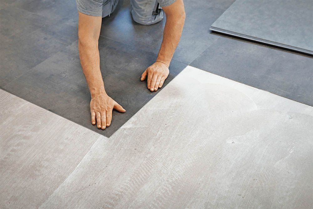 Ein Mann verlegt in einem Raum einen Vinylboden.