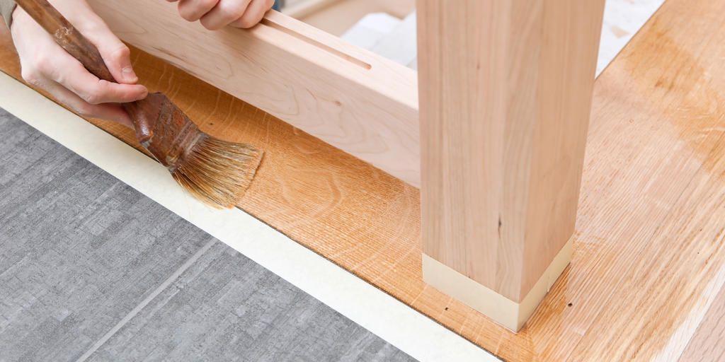 Eine Person streicht ein Stück Holz mit einem Pinsel.