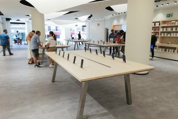 Eine Gruppe von Leuten steht in einem Geschäft um Tische herum.