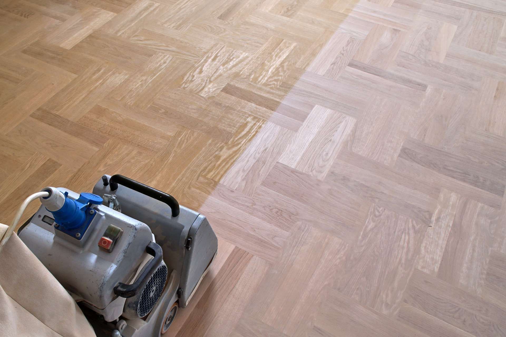 Eine Person schleift mit einer Maschine einen Holzboden.