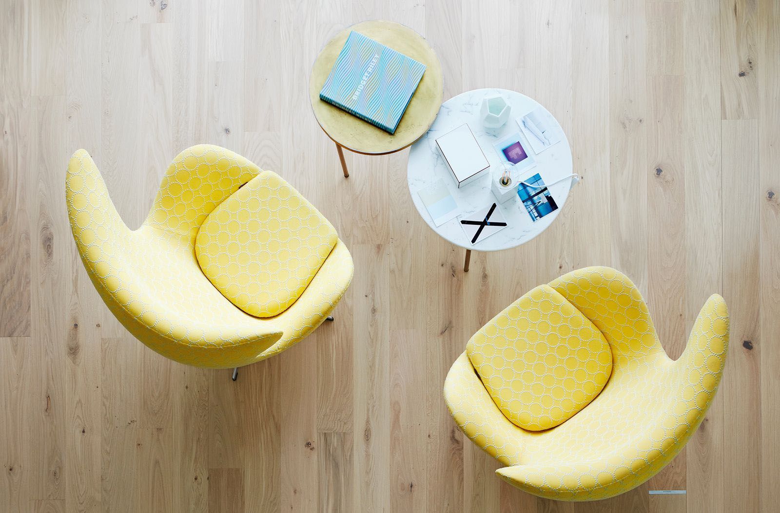 Zwei gelbe Stühle stehen neben einem Tisch, auf dem ein Buch liegt.