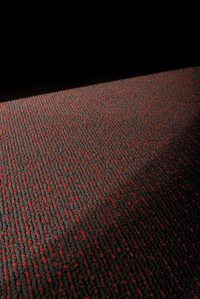 Eine Nahaufnahme eines rot-schwarzen Teppichs in einem dunklen Raum.