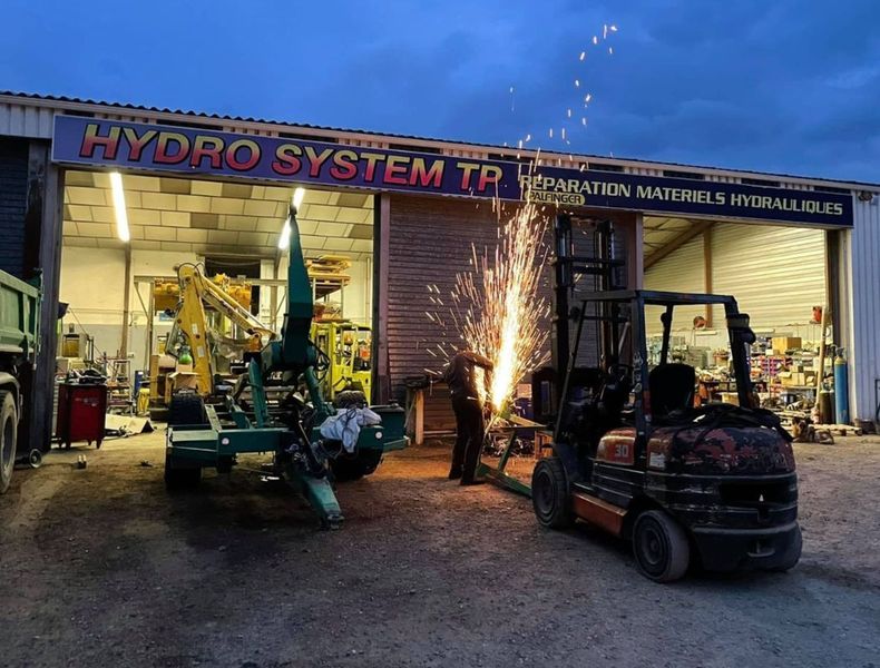 Des étincelles jaillissent d'un chariot élévateur lors d'une soudure à l'extérieur de l'atelier d'HYDRO SYSTEM TP.