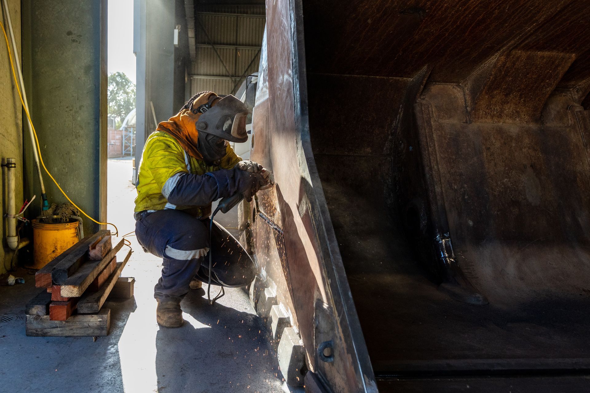 Un ouvrier en tenue de sécurité inspecte une grande structure métallique sur un site industriel.