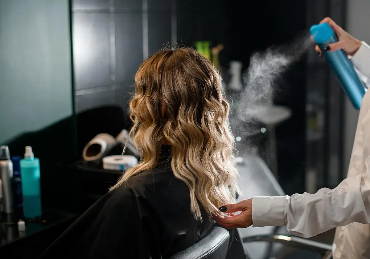 Una mujer se está pintando el cabello con spray en un salón.