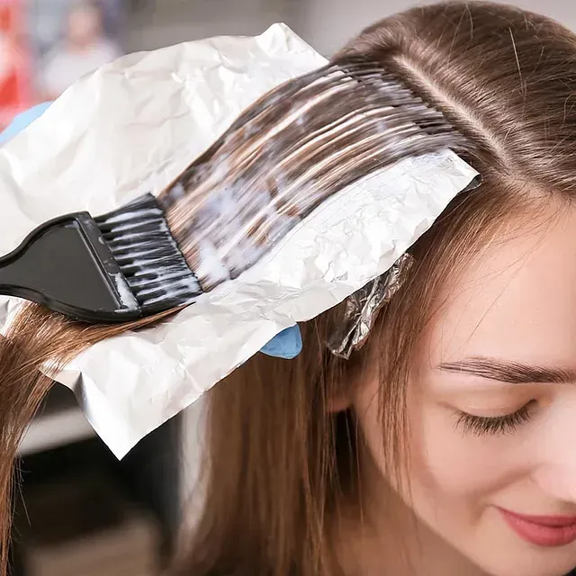 Una mujer se está tiñendo el cabello con un cepillo.