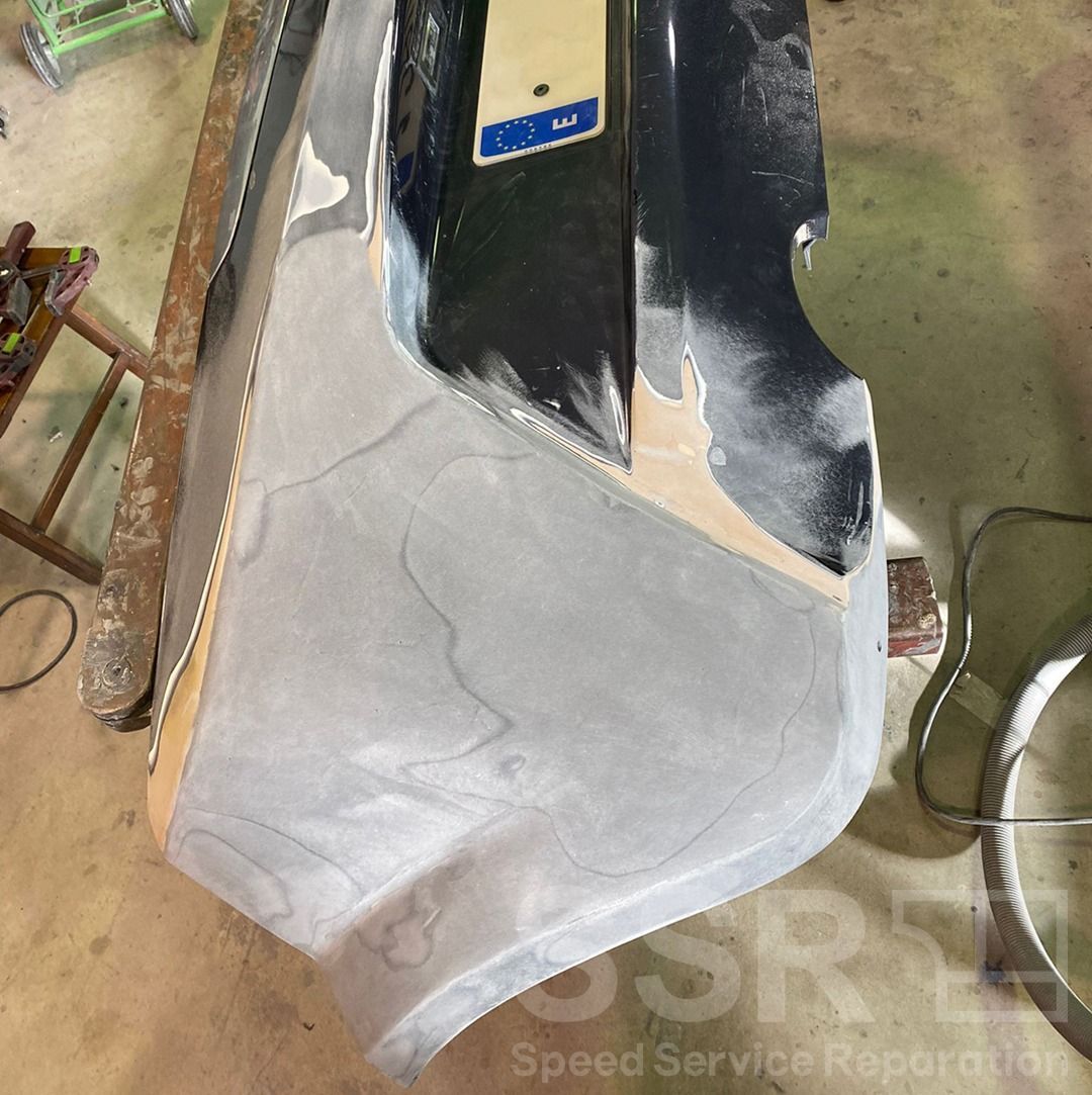 En un garaje se está reparando el parachoques de un coche.