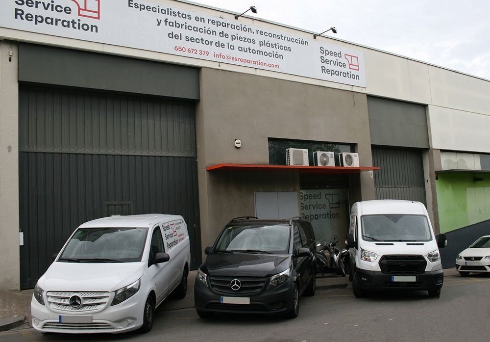 Tres camionetas están estacionadas frente a un edificio que dice reparación de servicios