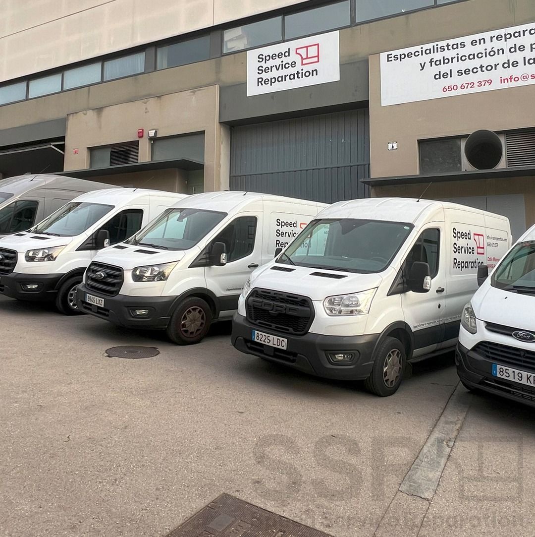 Una fila de furgonetas blancas estacionadas frente a un edificio.