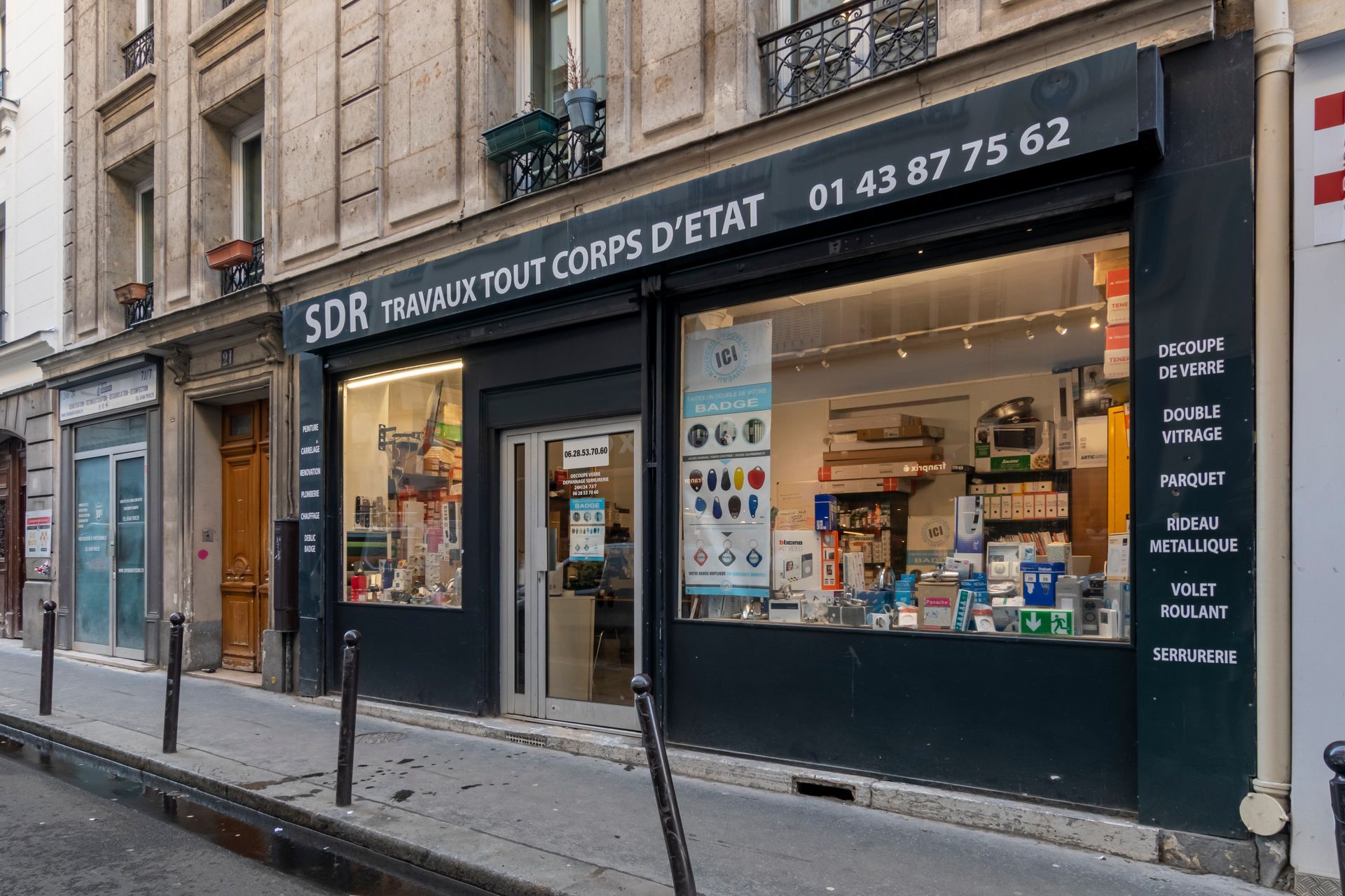 Façade d'un magasin parisien avec une façade noire, des vitrines et une enseigne indiquant « SDR Travaux tout corps d'état »